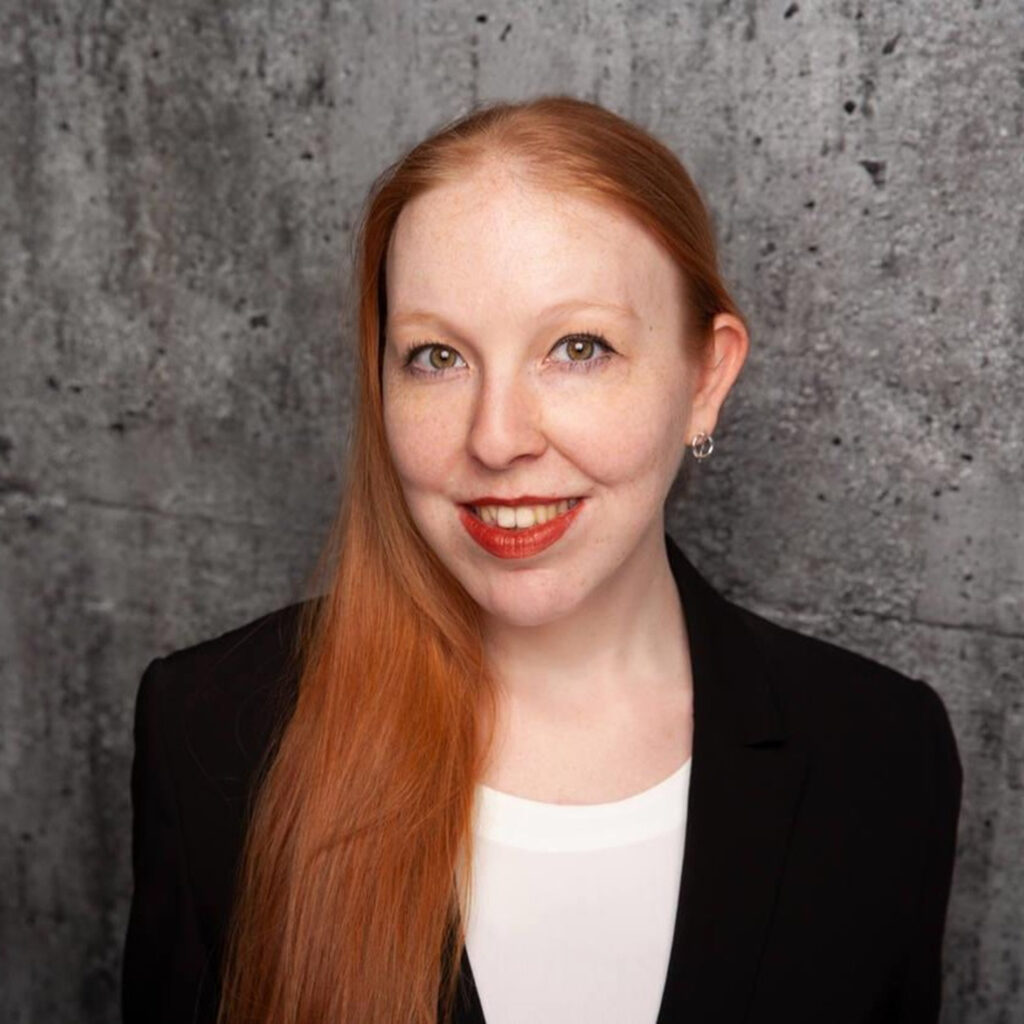 Profilbild von K. Egermann-Schuler, mit langen roten Haaren zum Zopf gebunden