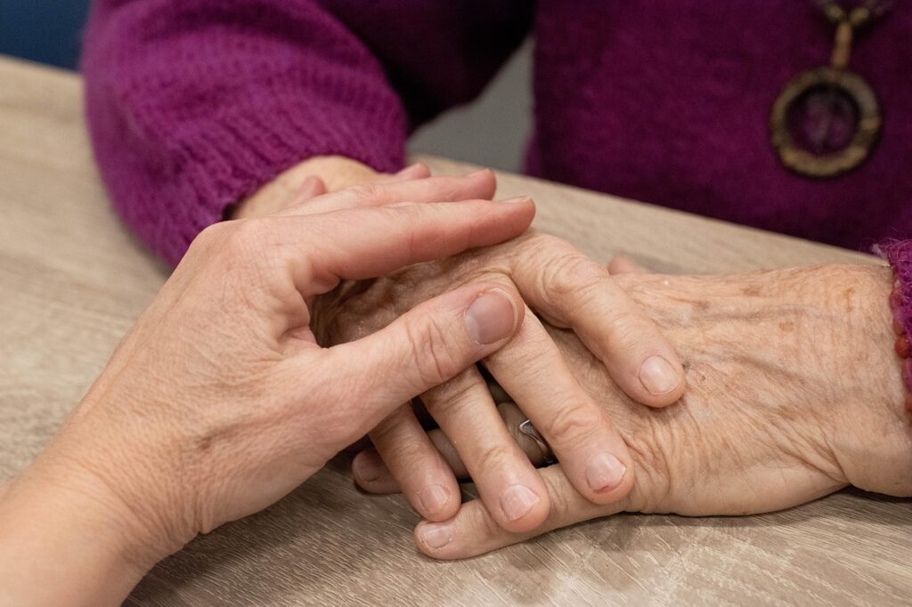 Eine Hand liegt beruhigend auf den Händen einer weiteren Person