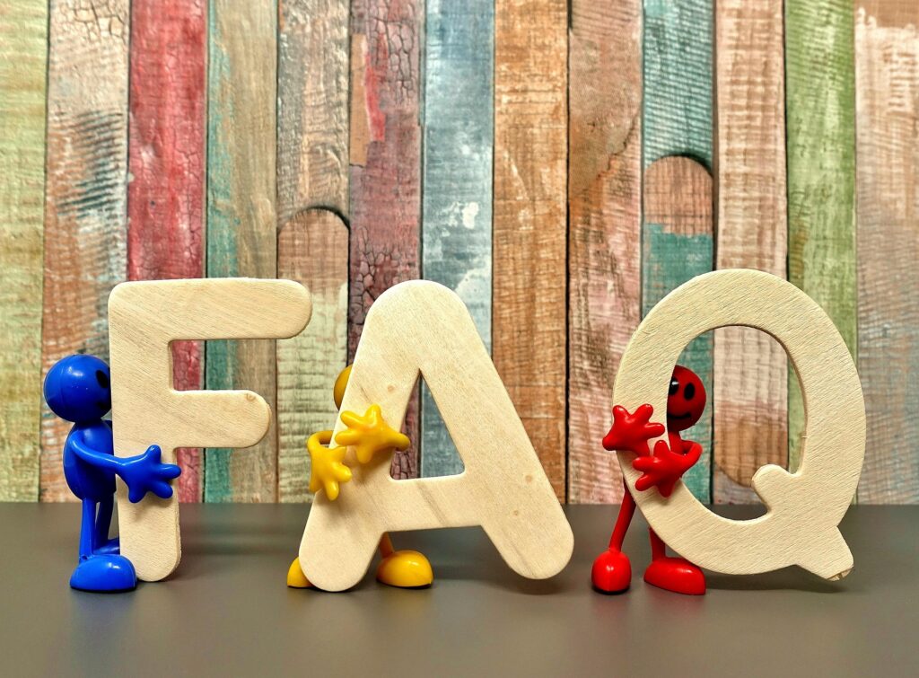 Die Buchstaben FAQ mit einem bleuen, gelben und roten Männchen vor einer bunten Wand