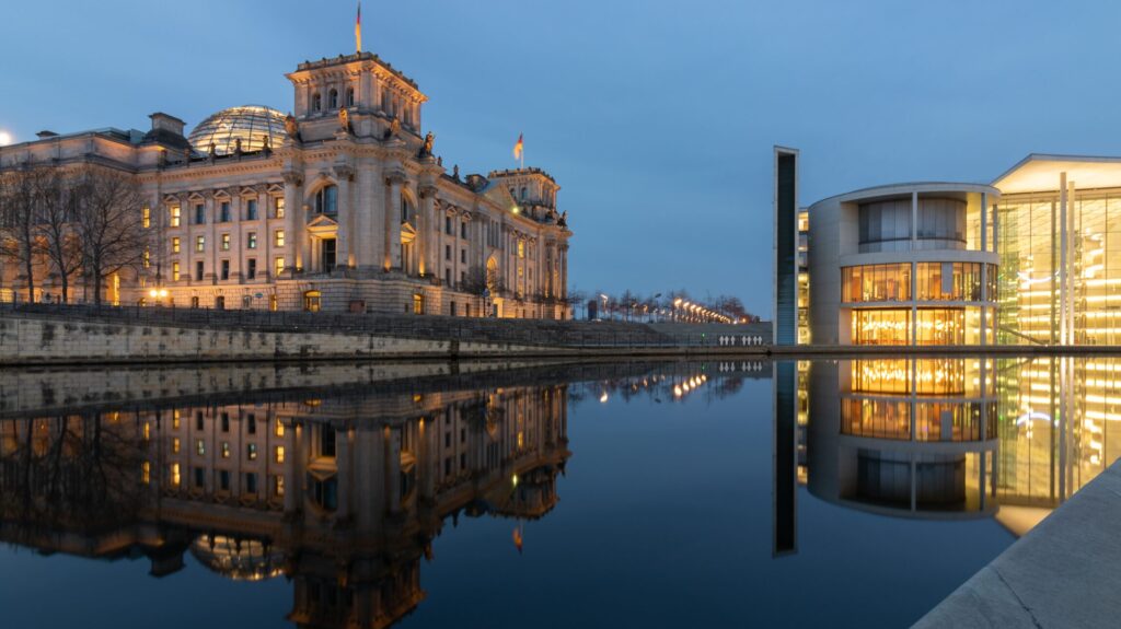 Das beleuchtete Reichstagsgebäude spiegelt sich im Morgen in Berlin